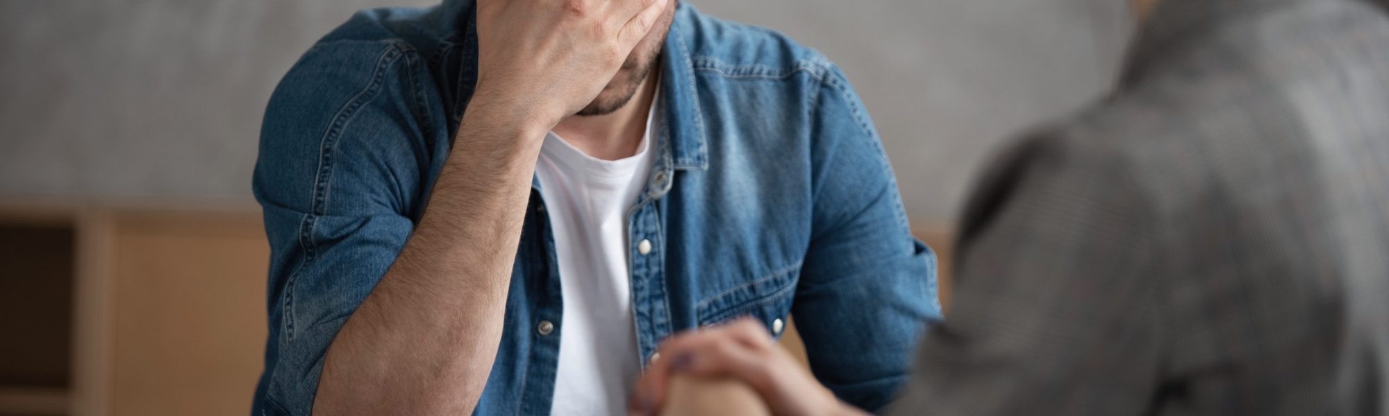 Psychologist talking with patient on therapy session. Depressed man speaking to a therapist while she is taking notes